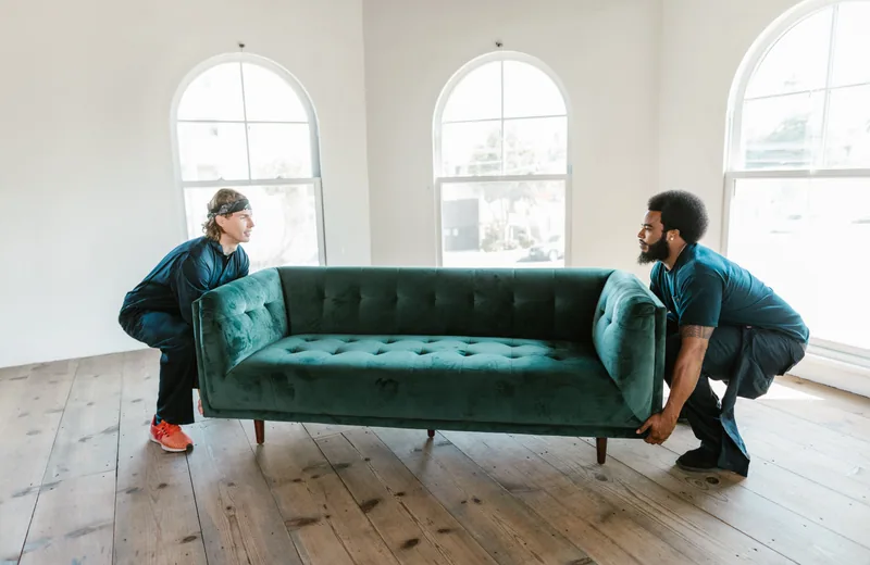 Two people lifting a sofa for furniture removal